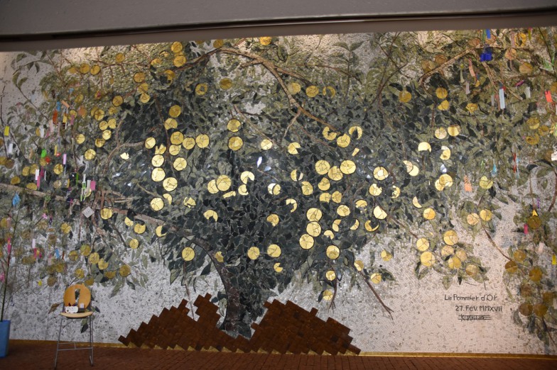 壁の両サイドに竹笹が飾られている。中央の大きな木は、自然石で描かれた壁画『Le Pommier d’Or 黄金の林檎』